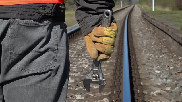 Railroad worker with adjustable wrench on railway in spring
