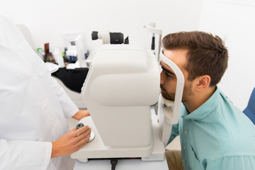 Fototapeta premium optician with autorefractor and patient at clinic