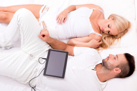 Beautiful young couple using a Tablet PC in Bed	