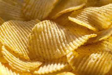 Background of ridged potato chips with spices. Closeup