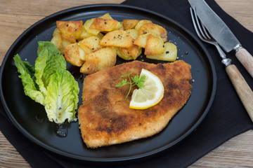Schnitzel mit Bratkartoffeln Salat und Zitrone