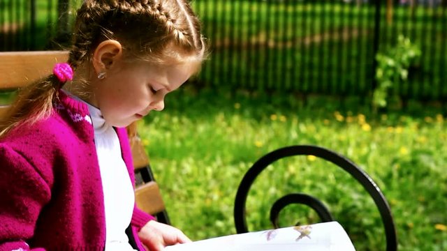 Girl reading a book while sitting on the bench