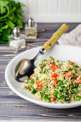 Couscous salad with parsley and tomatoes on wooden background. Selective focus. Eastern cuisine