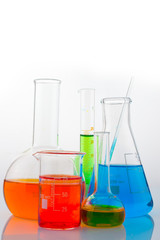 Different laboratory glassware with color liquid with reflection on white background