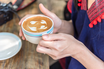 hand holding coffee cup above wooden table,