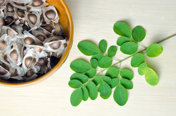 Moringa leaf and seed on wooden board background