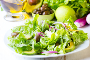 Green salad and ingredients lettuce, avocado, olives, oil, herb onion