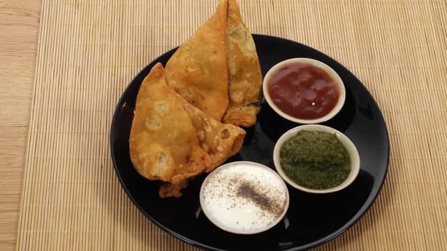 Tilt down to a plate of Samosa served with chutney, Indian savoury snacks