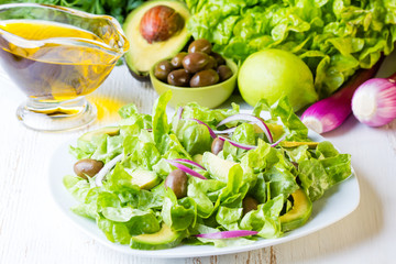 Green salad and ingredients lettuce, avocado, olives, oil, herb onion