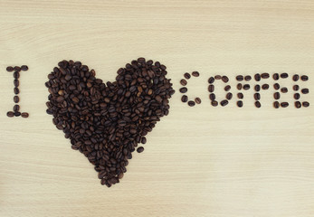 Coffee beans in the form of heart close up on a wooden background