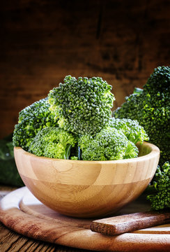 Fresh green broccoli in a wooden bowl on dark wooden background,