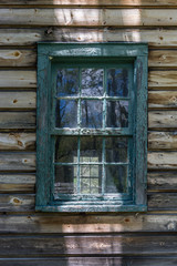 Vintage window with blue framing on weathered clapboard sided building