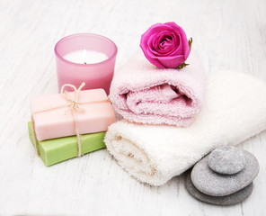 Obraz na płótnie Canvas Bath towels, candle and soap with pink roses