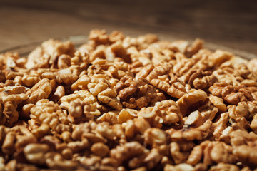 shelled walnuts on a plate, wooden background