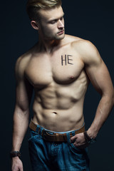 Fototapeta na wymiar Handsome muscular male model with intense glance posing over grey background. Perfect body with the inscription 