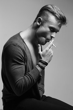  Emotive portrait of young fashionable model smoking  cigarette. Retro style. Close up. Black and white studio shot. 