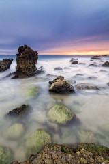 Long exposure seascape during blue hour sunset with rocks as for