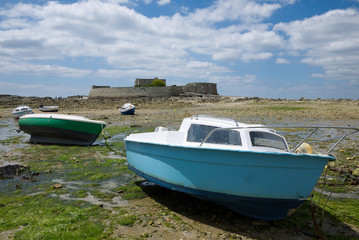 Bateaux en cale sèche devant un fort pendant la marée basse en Bretagne