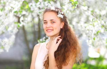 Spring portrait of a beautiful young girl with curly hair in flo