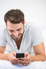 Close-up of man using mobile phone on bed