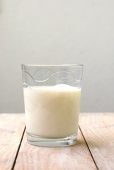 White milk in the glass with jug on the wooden background