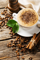 Close-up of coffee cup with roasted coffee beans on wooden backg