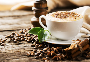 Close-up of coffee cup with roasted coffee beans on wooden backg