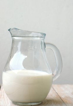White milk in the jug on the wooden background