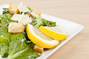 plate of ceasar salad with lemons slices