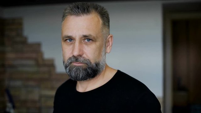 Client parikmazherskoy. Man aged with graying hair. Evaluates haircut beard and hairstyle. 