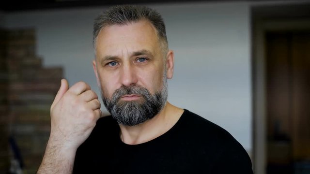 Client parikmazherskoy. Man aged with graying hair. Evaluates haircut beard and hairstyle. 