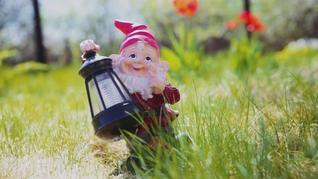 garden gnome - lamp standing on the grass in the garden amid the flowers