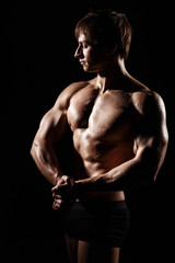 Naklejka premium Muscular and fit young bodybuilder fitness male model posing over black background. Perfect fitness WET body with DROPS. Ideal for commercial. ABS