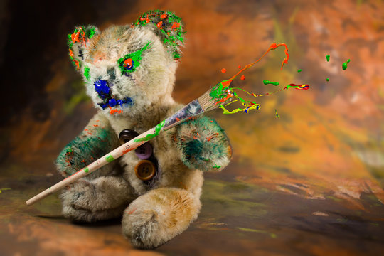 Magic paintbrush in a hand of a painted teddy bear