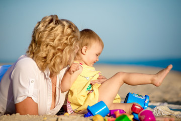 Mama with a daughter playing on the beach