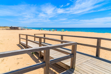 Wooden footbridge to sandy beach in Armacao de Pera coastal town, Algarve region, Portugal