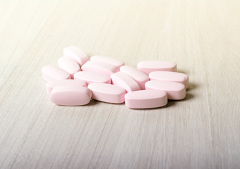 Obraz na płótnie Canvas Pink probiotic pills or vitamins on a wooden background.