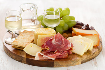 prosciutto with cheese and white wine in wooden board on white background