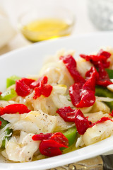 fish salad with pepper on white dish on white wooden background