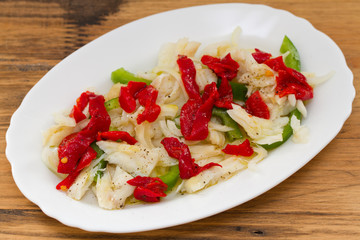 fish salad on white dish on brown wooden background