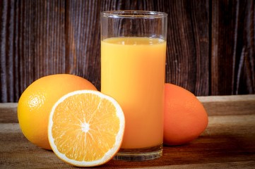 Frisch gepresster Orangensaft im Glas, vor einer  Holzwand