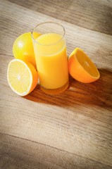 Orangensaft im Glas mit Orangen auf einem Holztisch, Hochformat