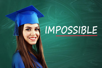 Young graduated woman near blackboard with word impossible transformed into possible