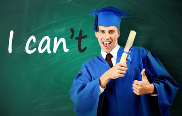 Young graduated man near blackboard with word impossible transformed into possible