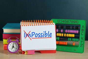 Word impossible transformed into possible on notebook page with school supplies