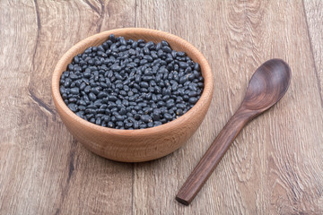 Bowl with beans and wooden spoon on a wooden background
