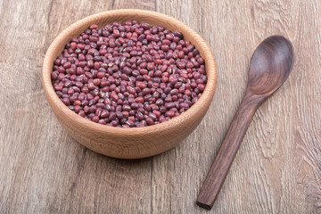 Bowl with beans and wooden spoon on a wooden background