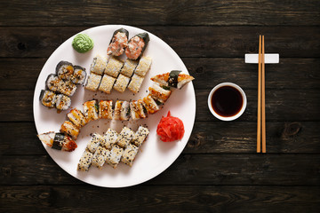 Fototapeta na wymiar Set of sushi maki and rolls at black rustic wood.