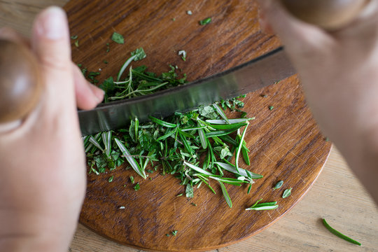Chopping aromatic herbs with italian mezzaluna knife. Selective focus.