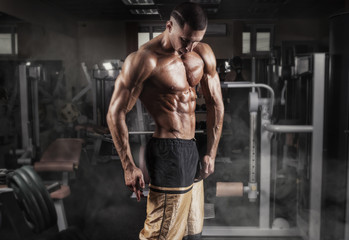 Fototapeta na wymiar Strong athletic man with muscular body in gym.
